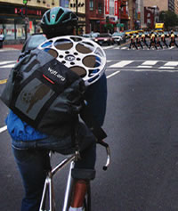 A courier risking his life biking on the streets of DC. His courier bag holds a valuable prize--a film reel.  He wears a helmet for his and our protection. Also a link to go to the home page.